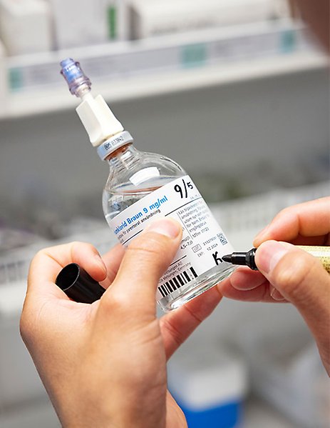 Pharmacist writing on a medicine bottle.
