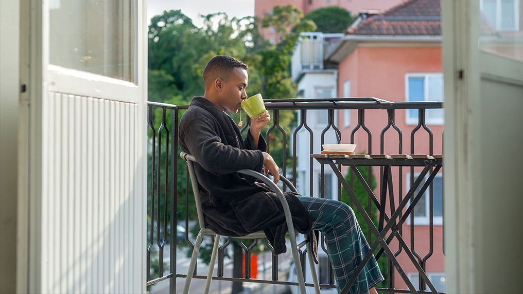 Student sitting on their balcony drinking coffee.