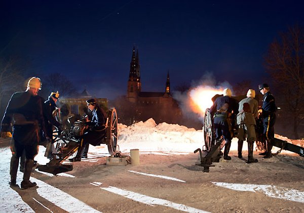 People dressed in uniforms firing the cannon beside the Castle early in the morning.
