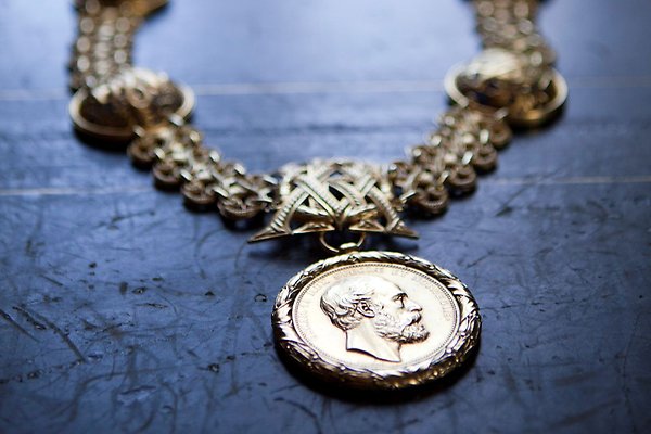 The Vice Chancellor's chain lying on a table. At the bottom of it is a portrait of Oscar the Second in profile.